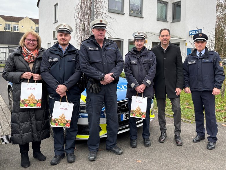 Le maire Wacht, accompagné d'employés du commissariat de police de Konz, devant le commissariat et une voiture de police, lors de la remise des sacs cadeaux.